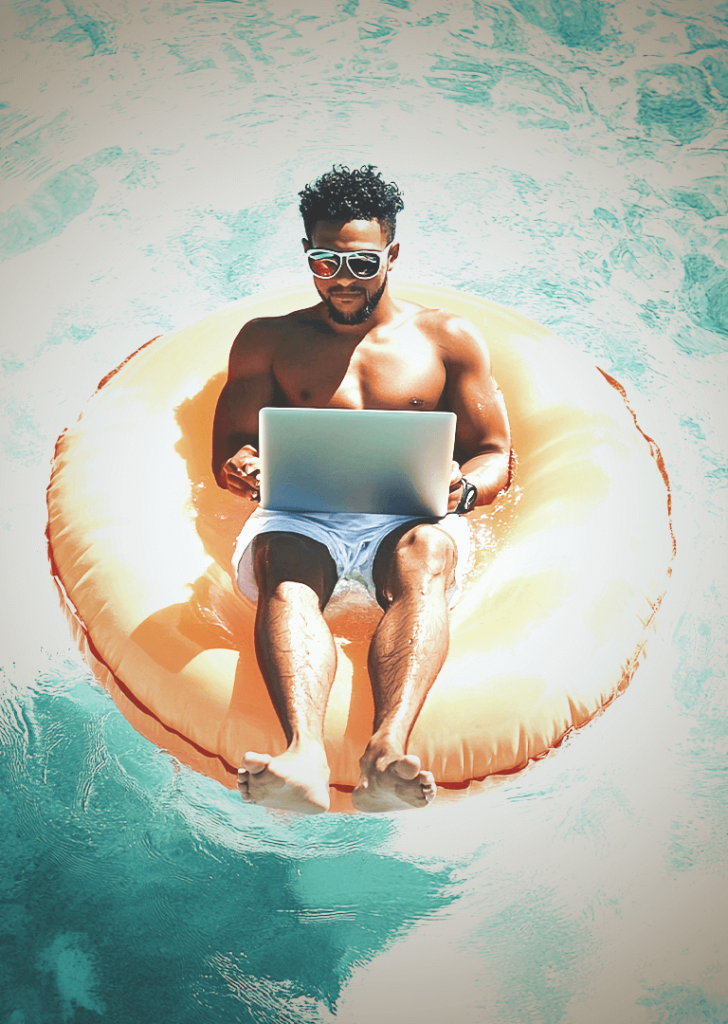 Mann der in einem Schwimmreifen im Pool liegt und am Laptop ist