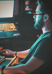 Mann der vor einem Gaming-Setup sitzt und arbeitet