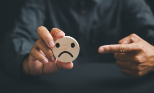 ein finger der auf einen traurigen smiley zeigt