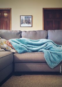 Quiet Vacationing eine Person liegt mit Wolldecke auf der Couch