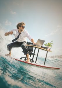 Work-Life-Balance Mann auf Surfbrett mit Schreibtisch