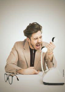 Ein Mann der in einen Telefonhörer reinschreit