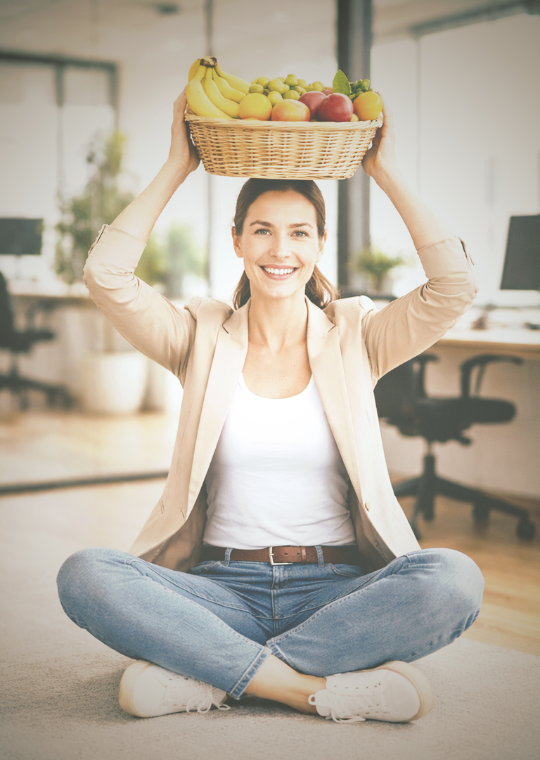 Mitarbeiterin nutzt Corporate Benefits: Sie macht Yoga im Büro mit Obstkorb über dem Kopf
